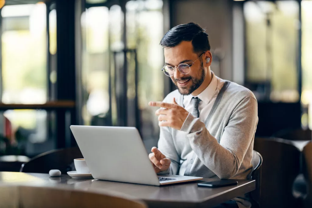 smart-casual man in glasses looks at computer whilst pointing